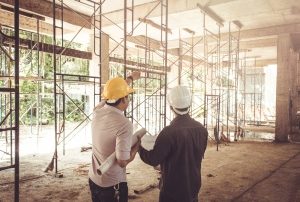 Builder and construction worker standing in a building under construction